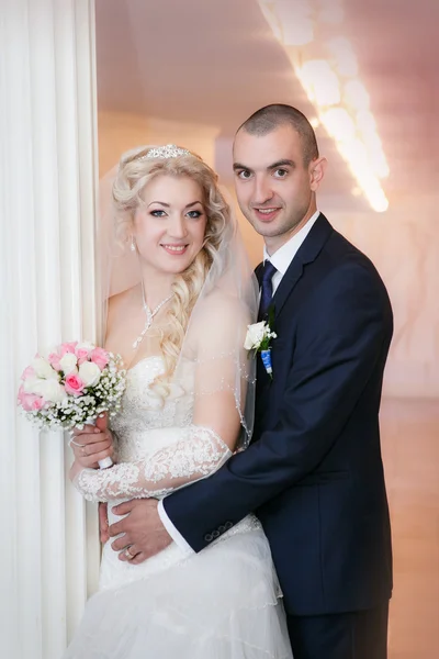 Groom and the bride stand near a white column — Stock Photo, Image