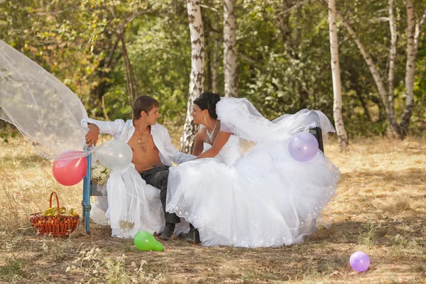 Brudgummen och bruden i skogen på en säng — Stockfoto