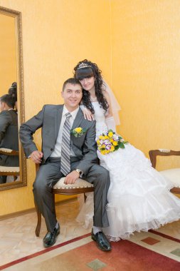 Gelin ve damat tahta sandalyede oturan