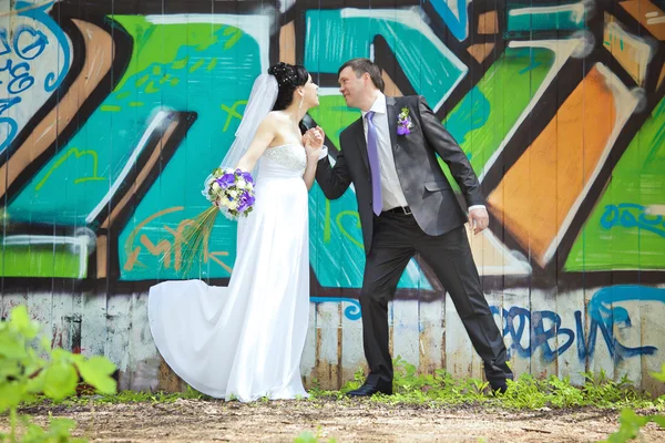 Allegro sposa e sposo che si tiene per mano su graffiti wal — Foto Stock