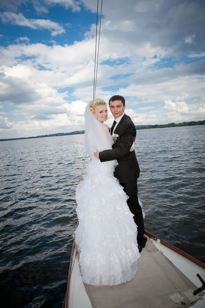 Happy bride and groom hugging on a yacht — Stock Photo, Image