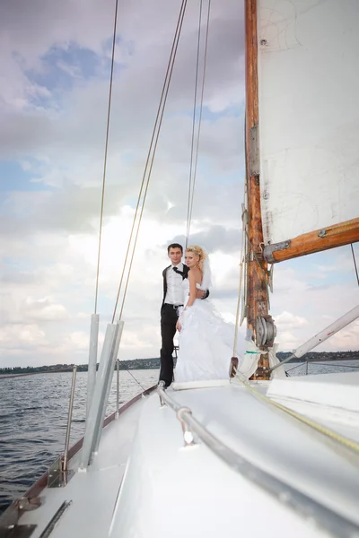 Lyckliga bruden och brudgummen kramas på en yacht — Stockfoto