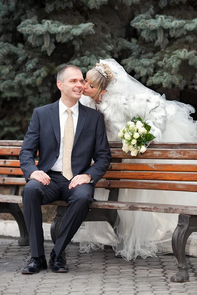 Lo sposo e la sposa in parco su una panchina — Foto Stock