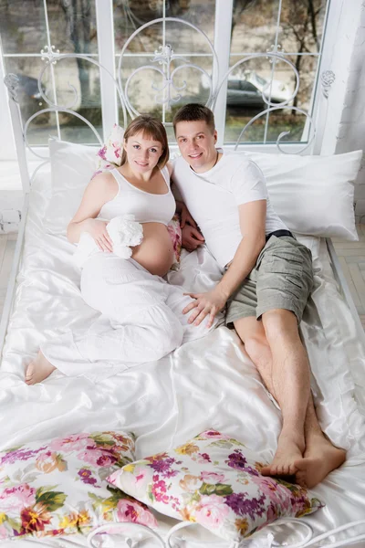 Mujer embarazada con su marido en el dormitorio — Foto de Stock