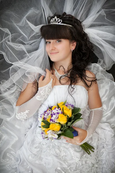 Portrait of the bride with a curly hair and a wedding bouquet from yellow roses