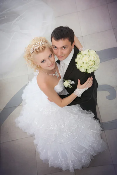 O noivo e a noiva com um buquê de casamento de rosas em uma mão olham para cima — Fotografia de Stock