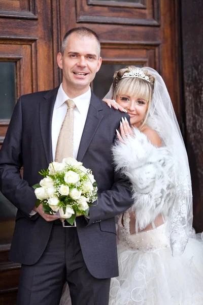 Bräutigam und Braut am Hochzeitstag vor einer Holztür — Stockfoto