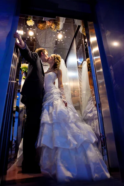 Kus van de bruidegom en de bruid in het hotel Lift — Stockfoto
