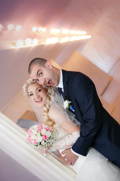 Groom et le stand de la mariée avec un bouquet de mariage près d'une colonne blanche — Photo