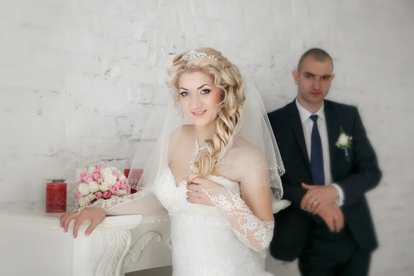 Beautiful bride an groom stand on their wedding day near fireplace — Stock Photo, Image