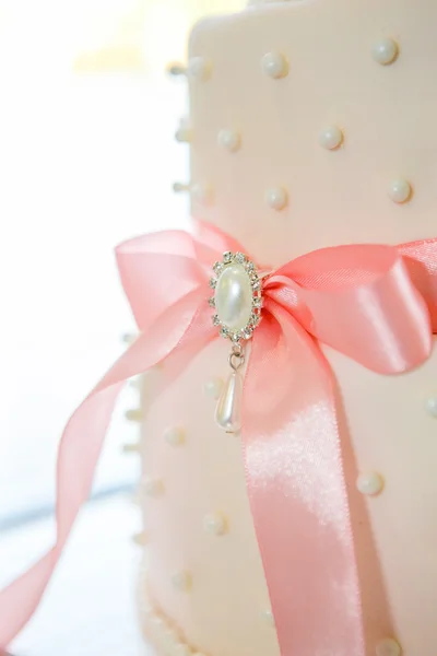 Bröllopstårta med vit glasyr och rosa rosett — Stockfoto