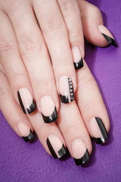 Female hands with black manicure on the violet background — Stock Photo, Image
