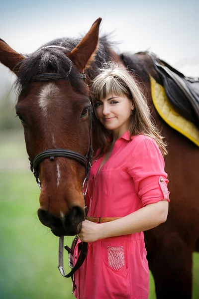 Ritratto della bella ragazza con un cavallo marrone nel parco — Foto Stock