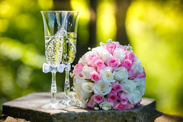 Huwelijksringen met rozen en glazen van champagne — Stockfoto