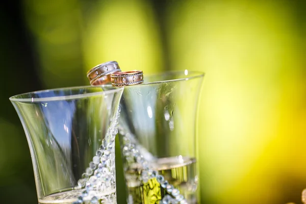 Wedding rings lie on champagne glasses — Stock Photo, Image