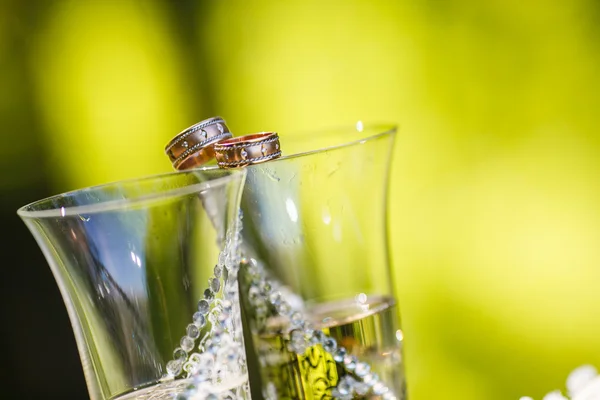 Wedding rings lie on champagne glasses — Stock Photo, Image