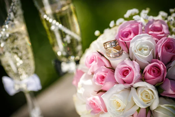 Huwelijksringen met rozen en glazen van champagne — Stockfoto