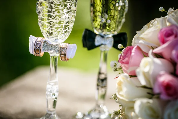 Huwelijksringen met rozen en glazen van champagne — Stockfoto