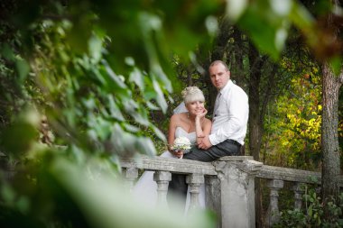 Şık gelin ve damat düğün günü dışarıda birlikte poz veriyorlar.