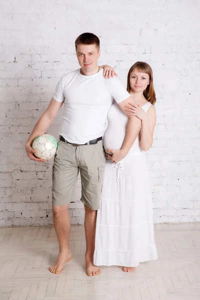 Belle femme enceinte et son mari amusant avec ballon de football — Photo