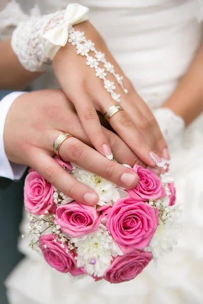 Mãos e anéis no buquê de casamento — Fotografia de Stock