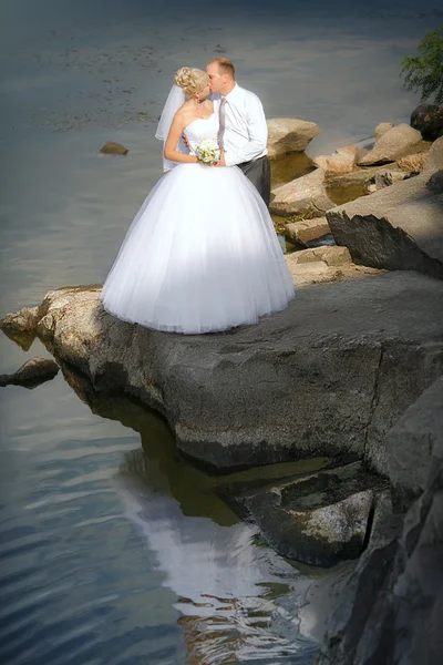 Bride and groom on the banks of the river — Stock Photo, Image