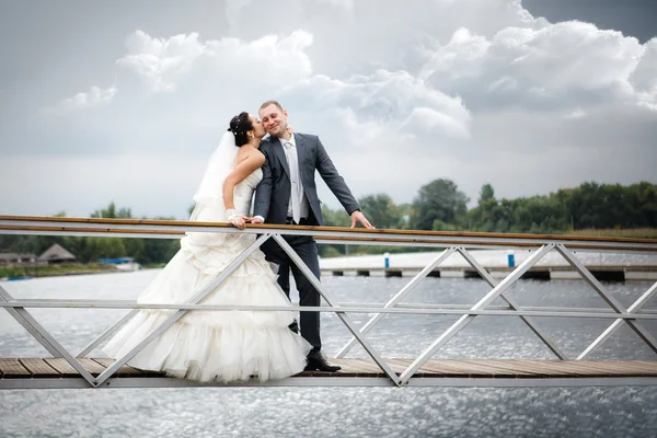 Young couple in love the bride and groom with a bouquet posing on a background pier with yachts, wedding day in the summer. Enjoying a moment of happiness and love. — Stock Photo, Image