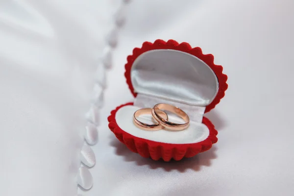 Joyero rojo con anillos de boda de oro en la tela blanca —  Fotos de Stock