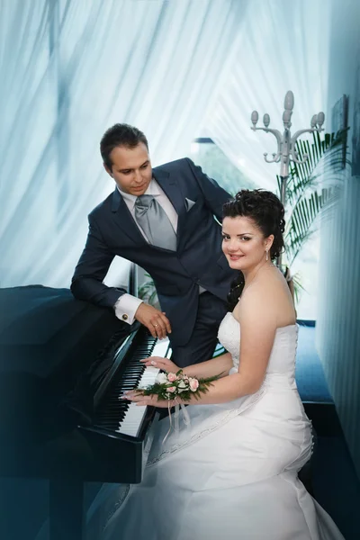 Ο γαμπρός και η νύφη κοντά σε ένα μεγάλο πιάνο — Φωτογραφία Αρχείου
