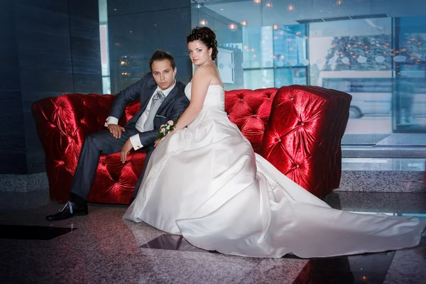 Beautiful groom and bride sitting in interior on wedding day — Stock Photo, Image