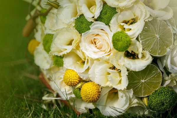 Wedding bouquet from beige roses, cinnamon, a lemon, a lime on a green grass — Stock Photo, Image