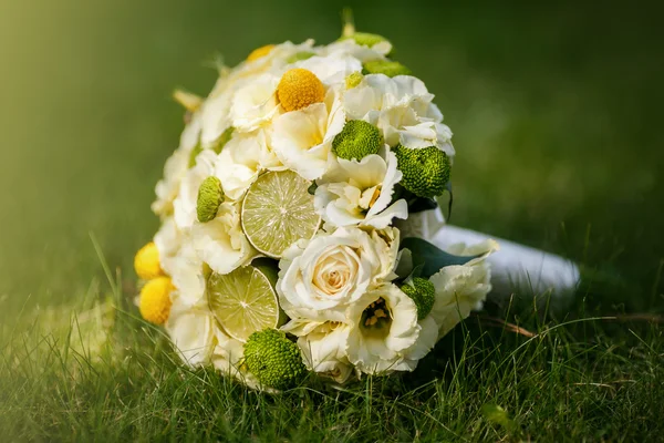 Bouquet nuziale da rose beige, cannella, un limone, una limetta su un'erba verde — Foto Stock