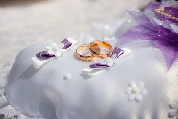 Anéis de casamento estão em um pequeno travesseiro — Fotografia de Stock