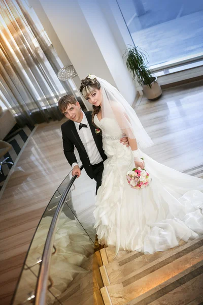Lyckliga bruden och brudgummen på stege på hotel — Stockfoto