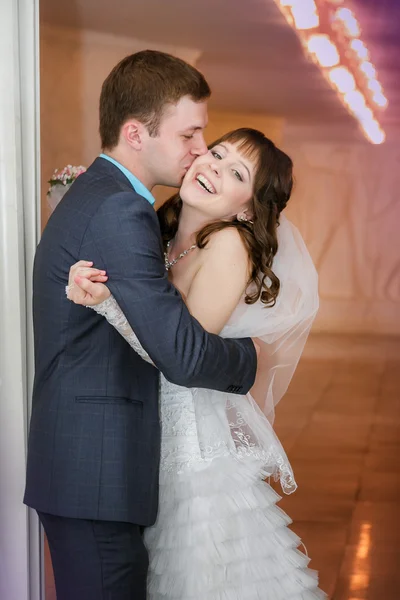Ženich a nevěsta s svatební kytice stojí poblíž bílý sloup — Stock fotografie