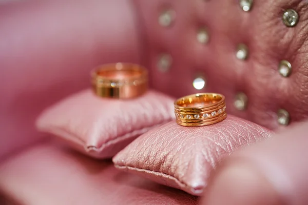 Anillos de boda en almohadas de color rosa primer plano —  Fotos de Stock