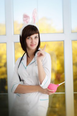 Bir sabahlık tavşan kulaklı seksi çekici hemşire. Lavman elinde tutan