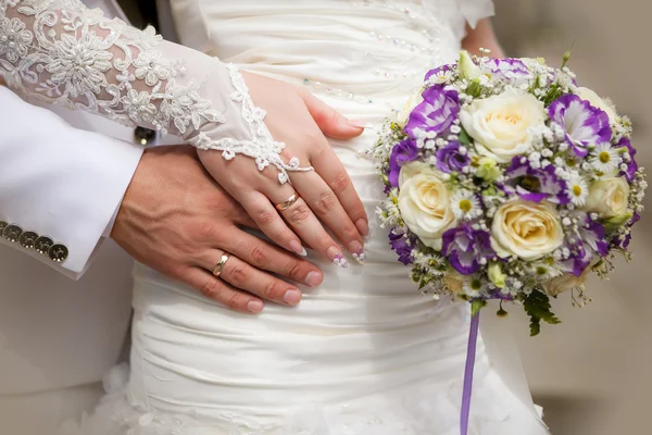 Mani di sposo e sposa con bouquet di nozze e anelli — Foto Stock