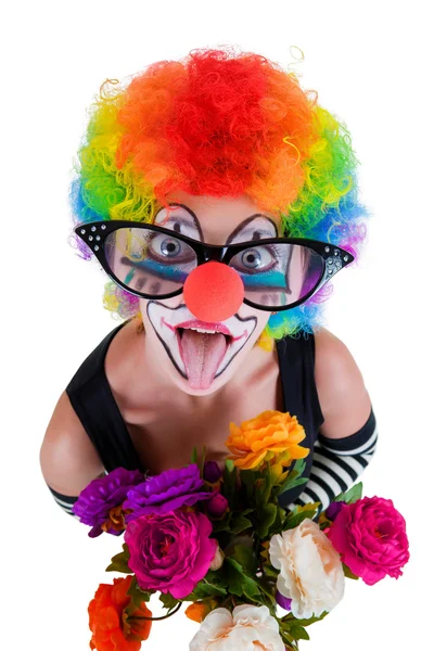 Mädchen in großer roter Brille und Clownskostüm mit Blumenstrauß streckt die Zunge heraus und blickt auf — Stockfoto