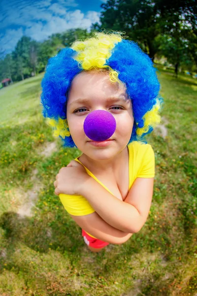 Chica divertida en peluca de payaso con nariz azul —  Fotos de Stock