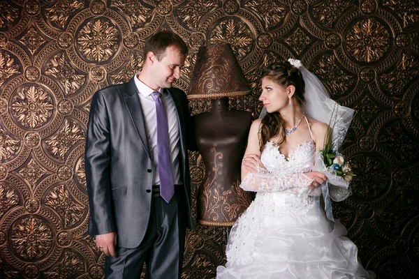 O noivo feliz e a noiva encantadora com um buquê de rosas no estúdio — Fotografia de Stock