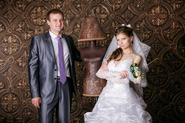 Счастливый жених и очаровательная невеста с букетом от Фес в студии — стоковое фото