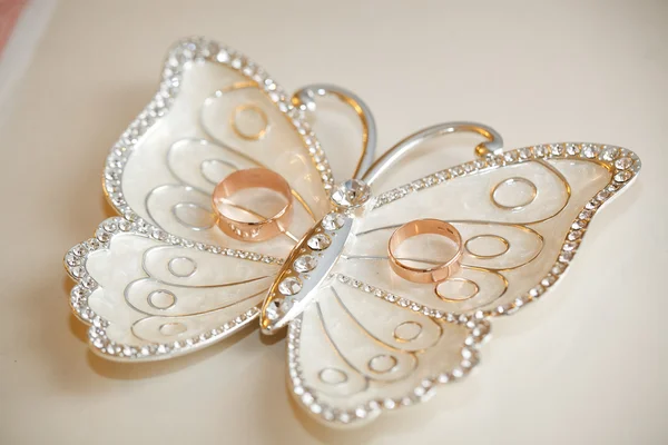 Wedding rings lie on a plateau in the form of a butterfly — Stock Photo, Image