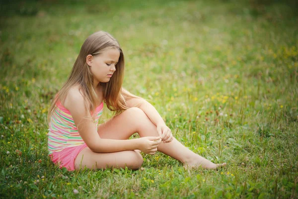 Дівчина сидить на зеленій траві на вулиці — стокове фото