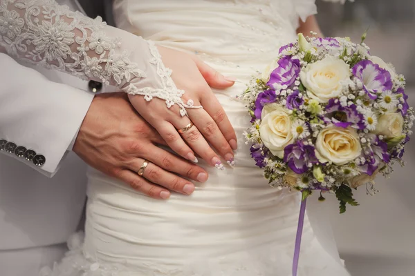 Manos de novia y novio con ramo de bodas y anillos — Foto de Stock