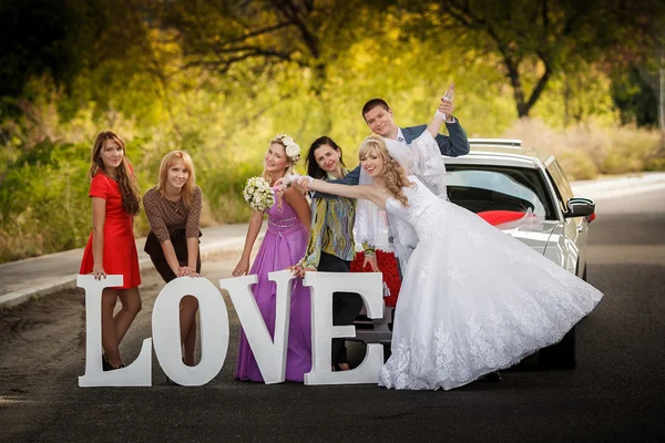 Happy bride and groom and bride's girlfriends on the road — Stock Photo, Image