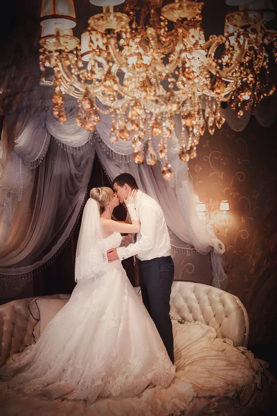 Happy brudgummen och bruden stå på en säng i ett sovrum eller i ett hotellrum — Stockfoto