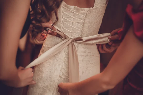 Noiva está colocando em seu vestido de casamento branco — Fotografia de Stock