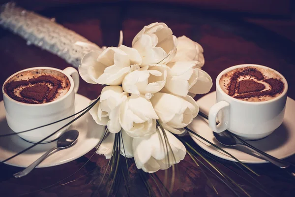 Two cups of coffee and white tulips