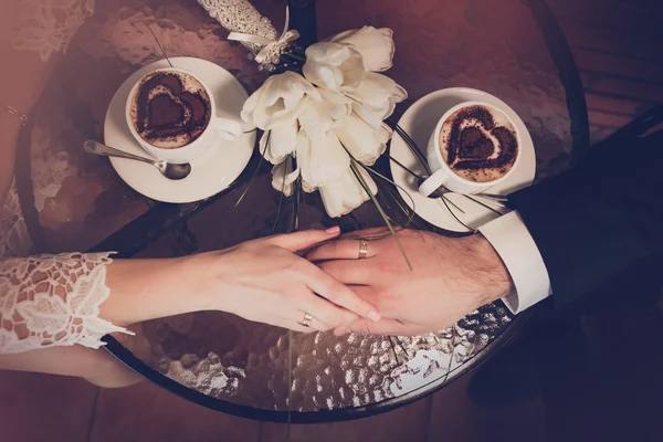 Dwie filiżanki kawy i ręki panny młodej i pana młodego z obrączki — Zdjęcie stockowe